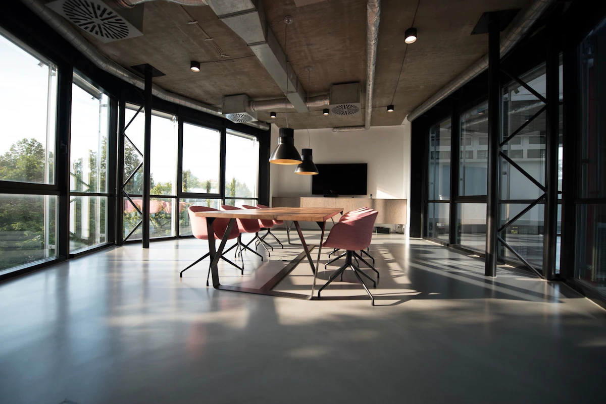 Commercial office meeting area with a table, chairs, windows, and polished floors